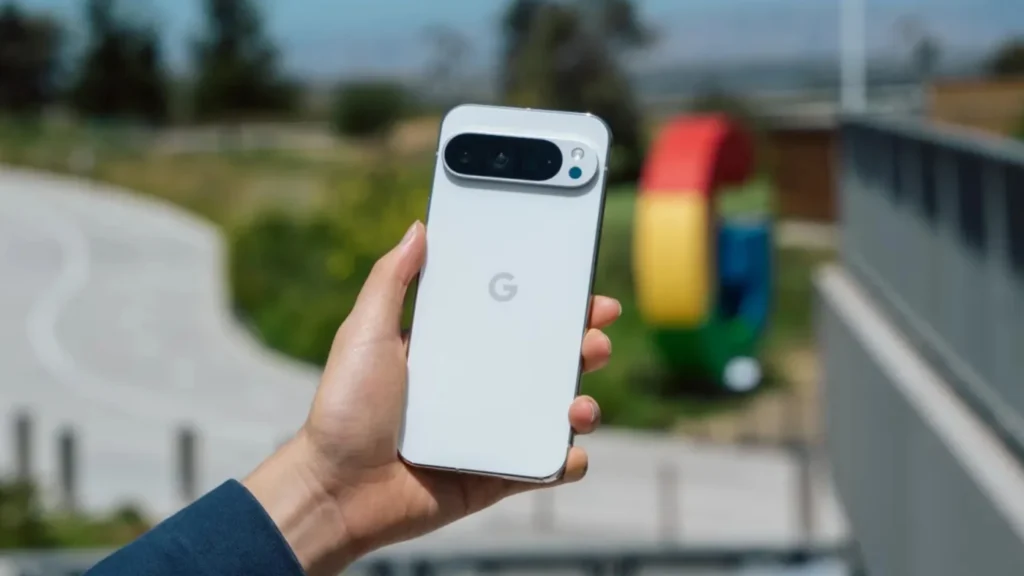 Mão segurando um smartphone branco do Google com câmera traseira horizontal, em ambiente externo com fundo desfocado.
